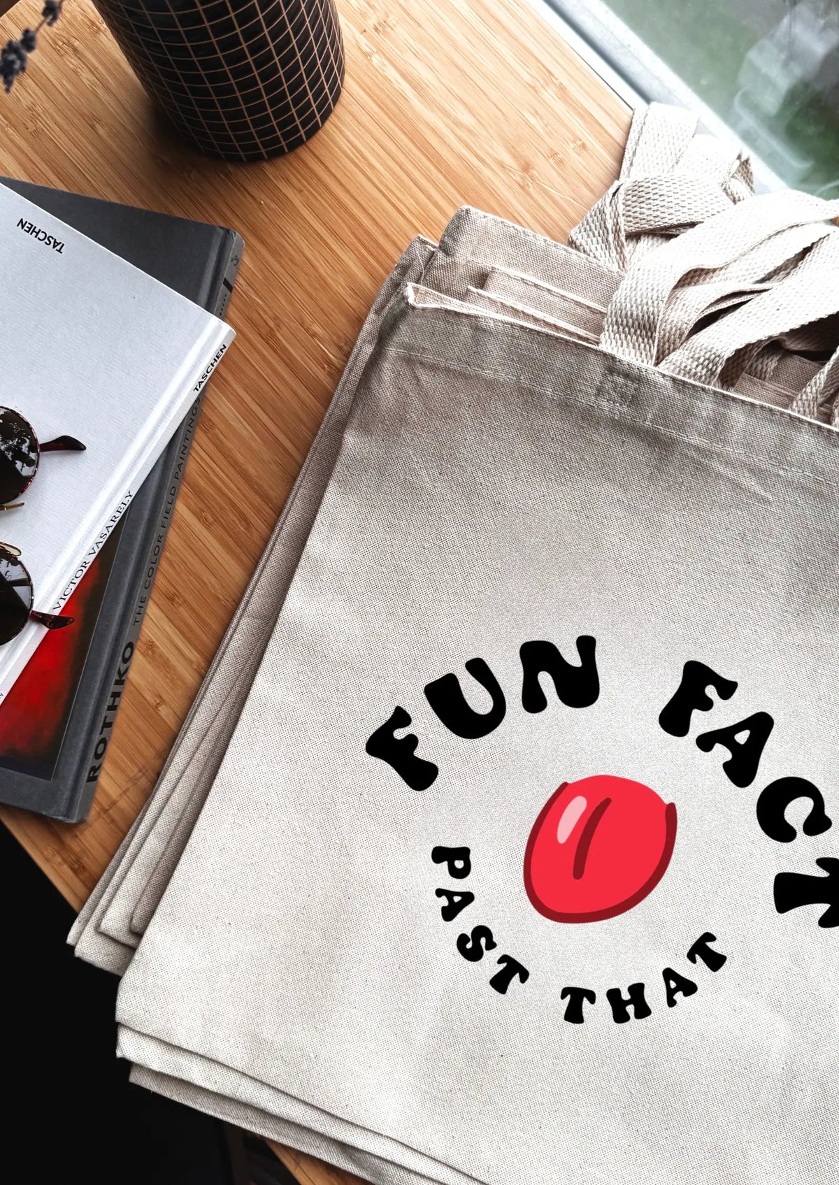 Gray tote bag with 'FUN FACT' design on a wooden surface