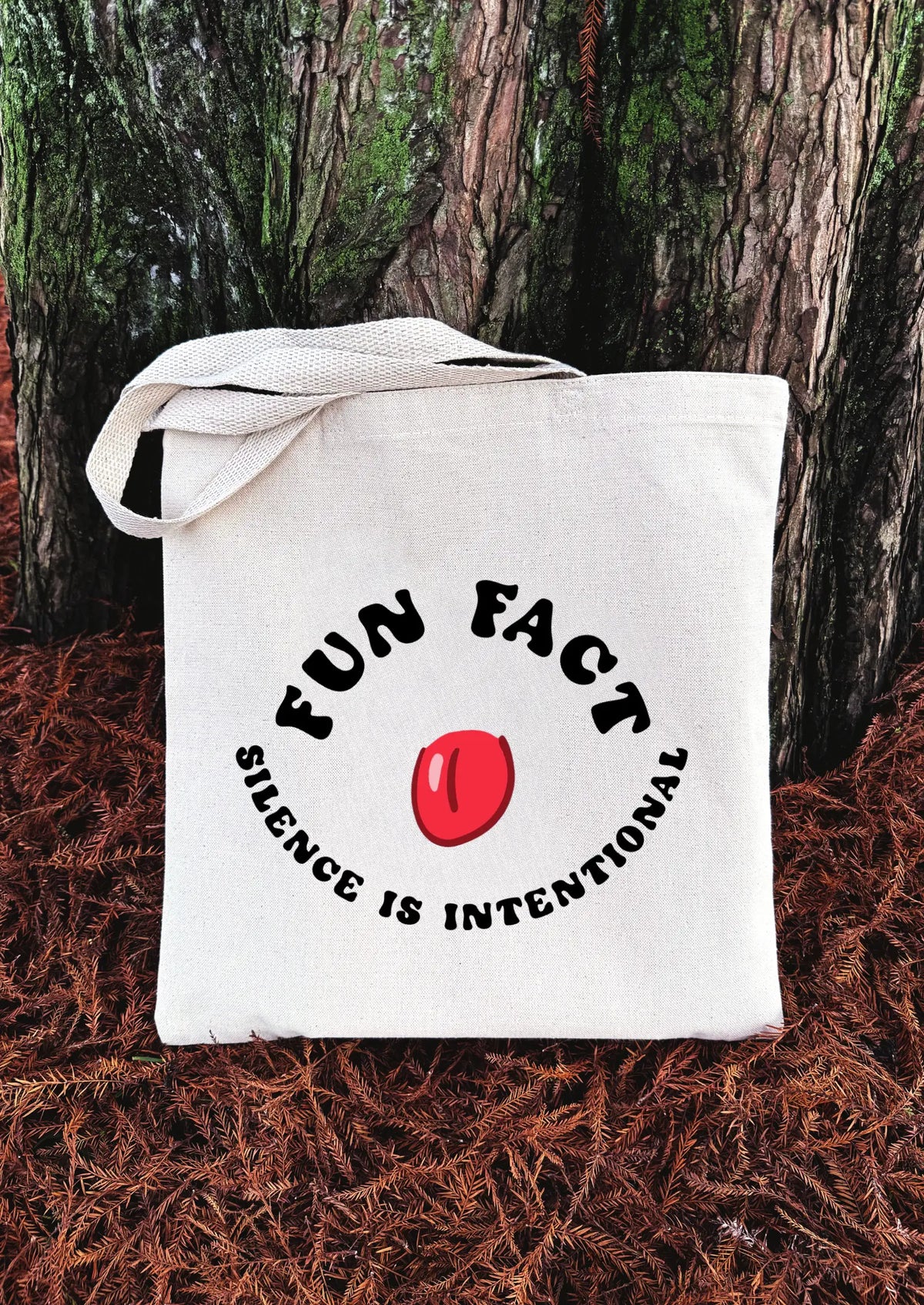 White tote bag with 'FUN FACT' and 'silence is intentional' text on a natural background