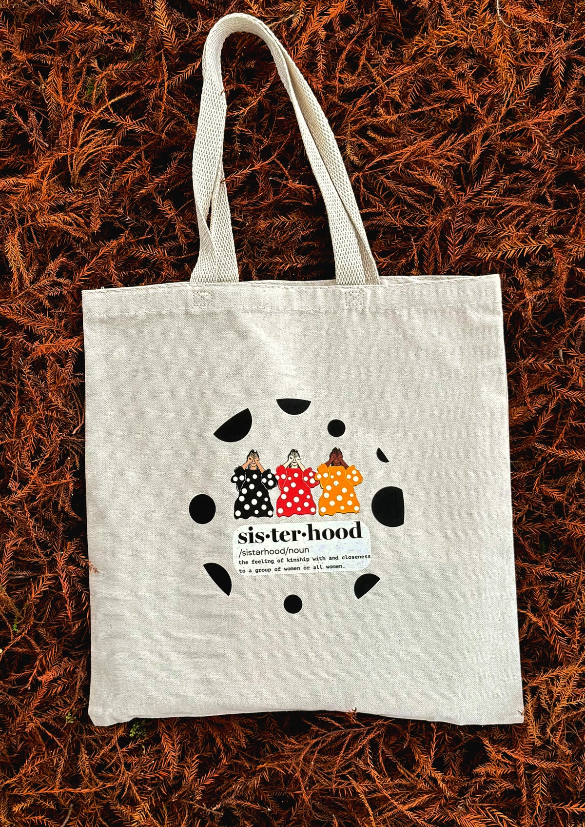 Sisterhood line art canvas tote bag laid flat outdoors on autumn leaves background