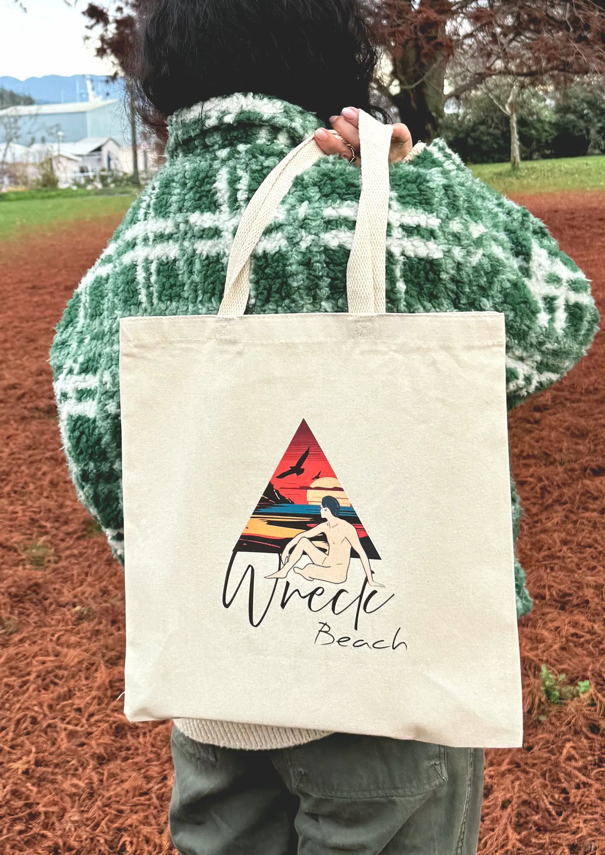 Wreck Beach line art canvas tote bag carried over the shoulder outdoors in a park setting