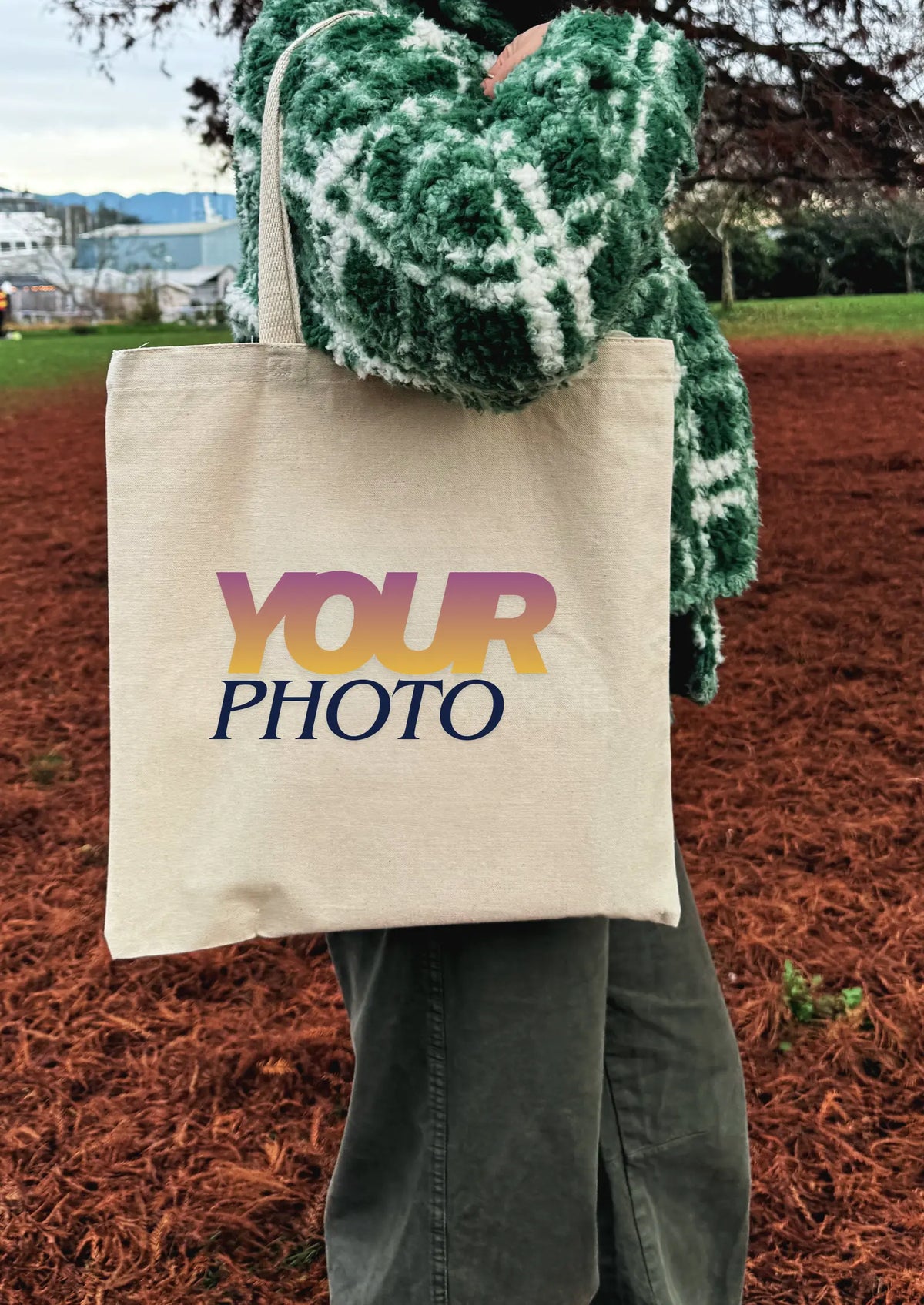 Beige tote bag with 'YOUR PHOTO' text held by a person outdoors.